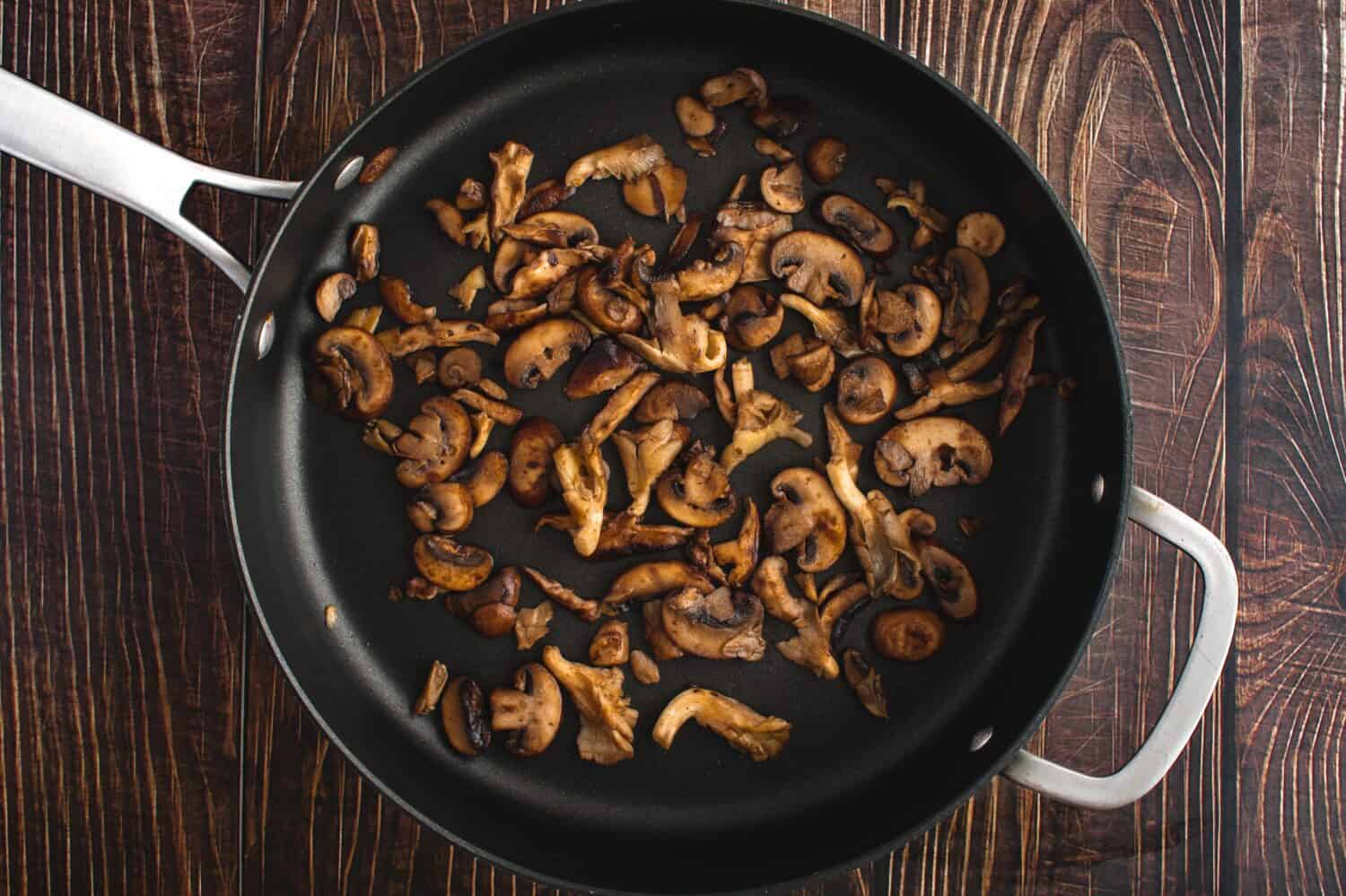 Browned Wild Mushrooms in a Non-stick Saute Pan Viewed from Above: Overhead view of oyster, shiitake, and crimini mushrooms cooked in butter
