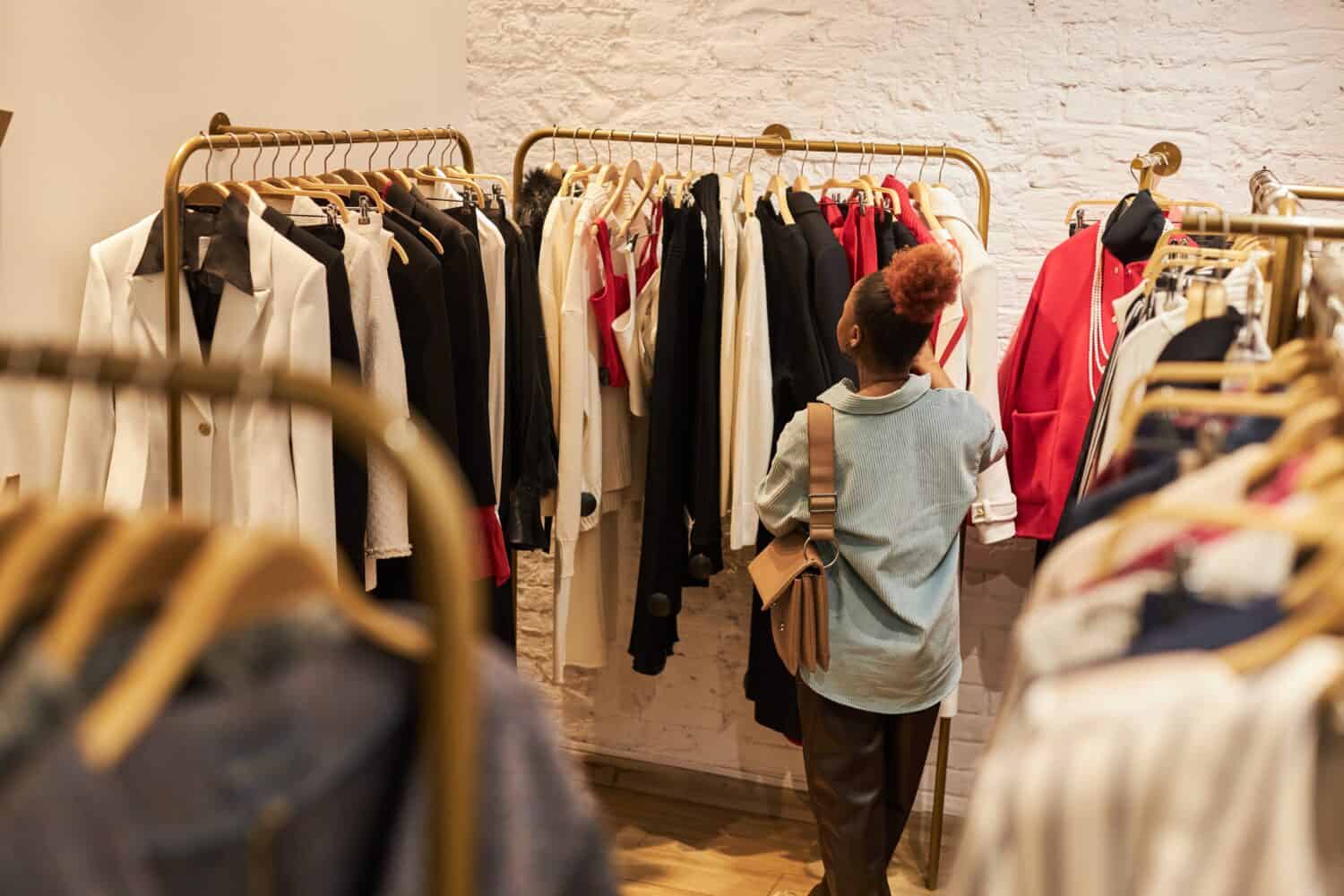 Back view at young black woman in boutque or second hand shop, copy space