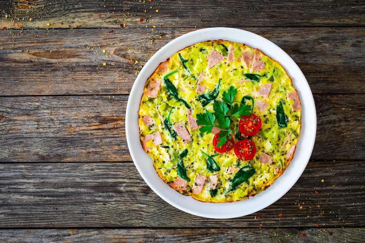 Delicious breakfast - egg omelette with mortadella, leek,spinach and cherry tomatoes on wooden table