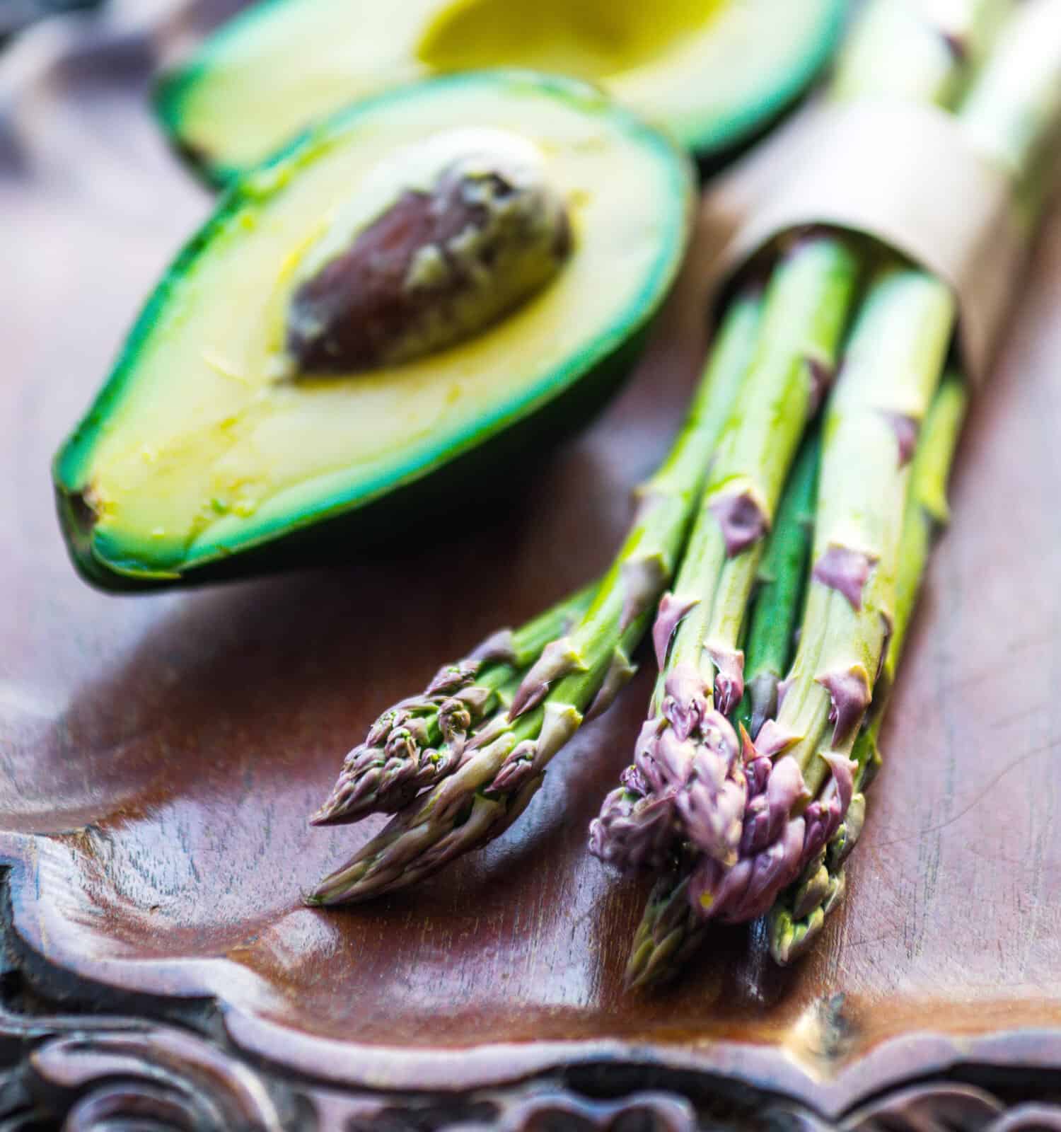 Bunch of fresh asparagus and avocado on wooden table