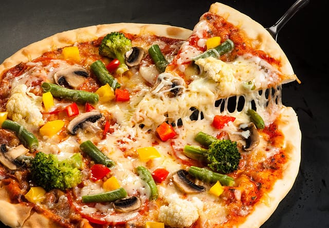 vegetarian pizza on a dark background with mushrooms, cheese and sweet pepper, cutting