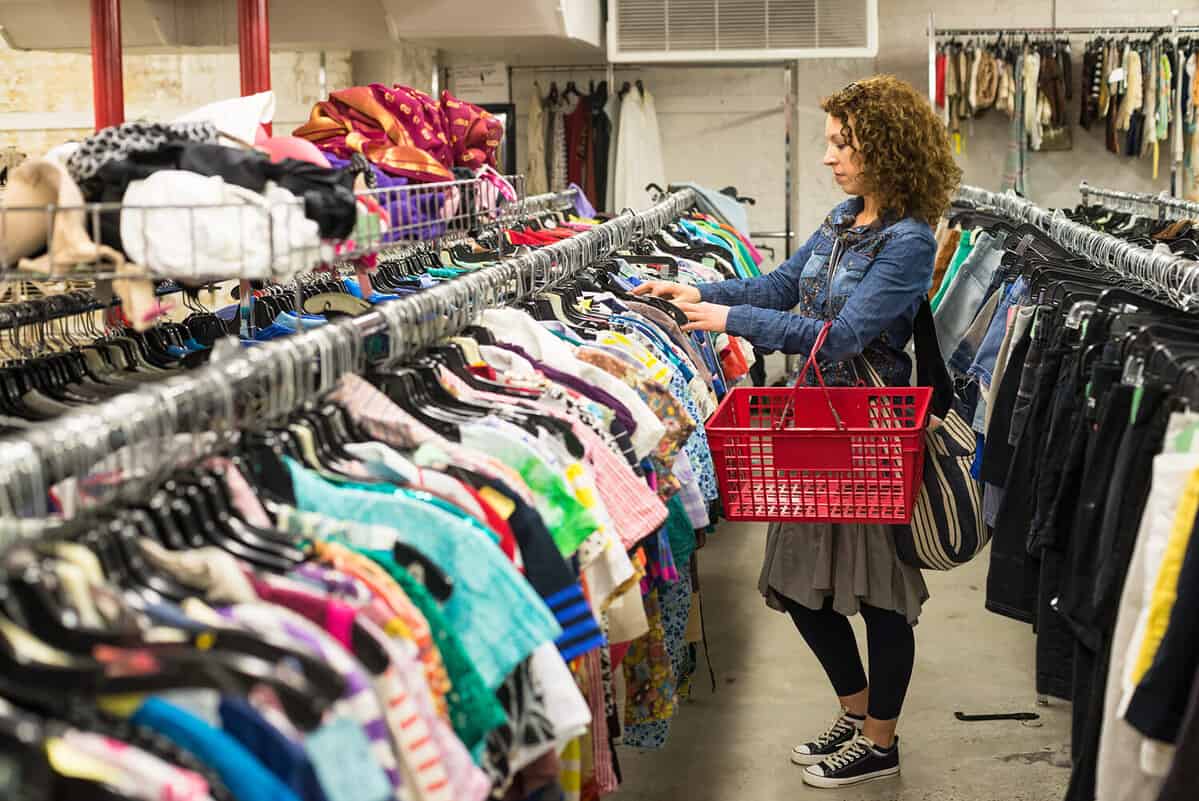 Female Shopper In Thrift Store browsing through clothing