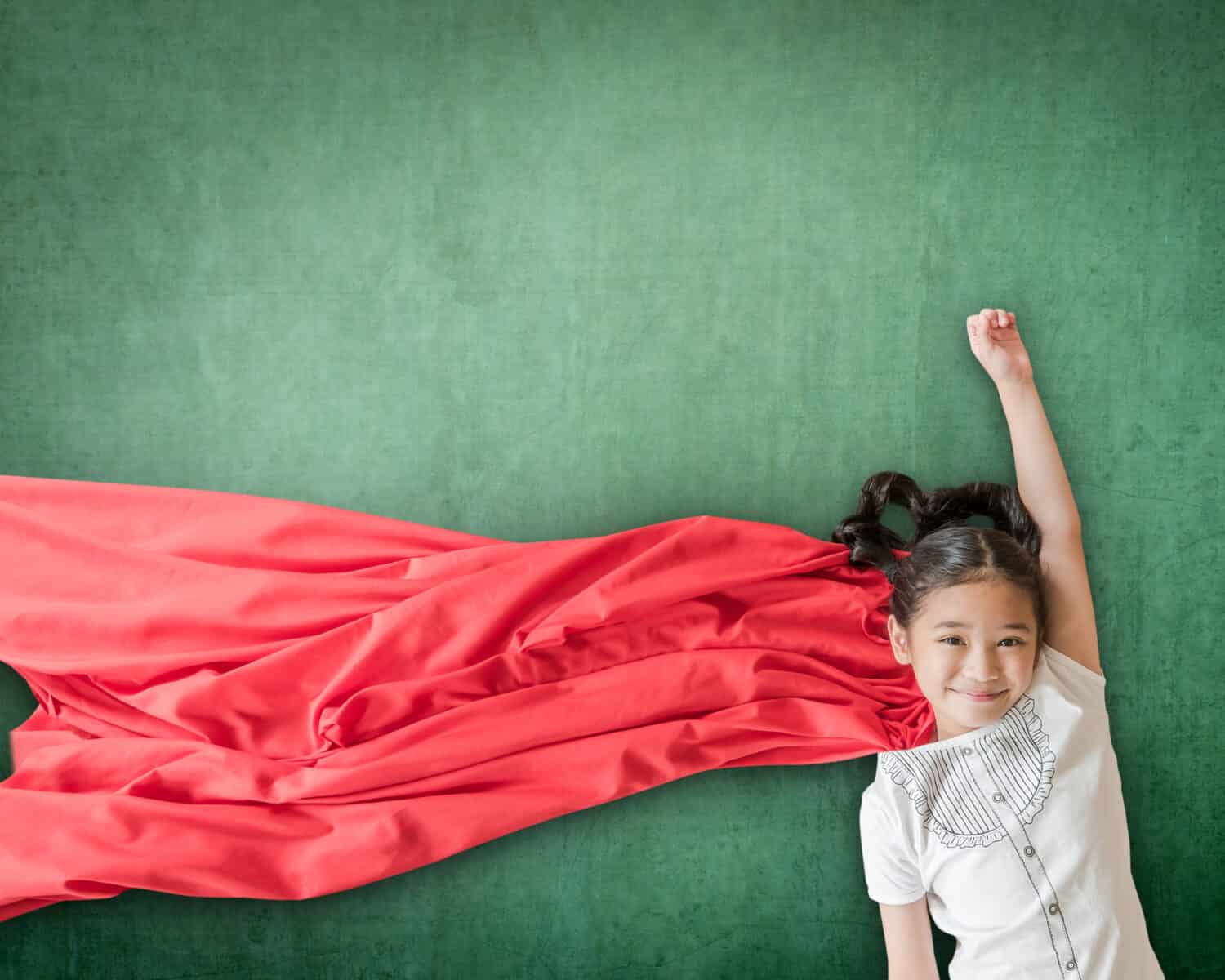 Superhero Asian school girl kid student with inspiration in women rights in education success concept