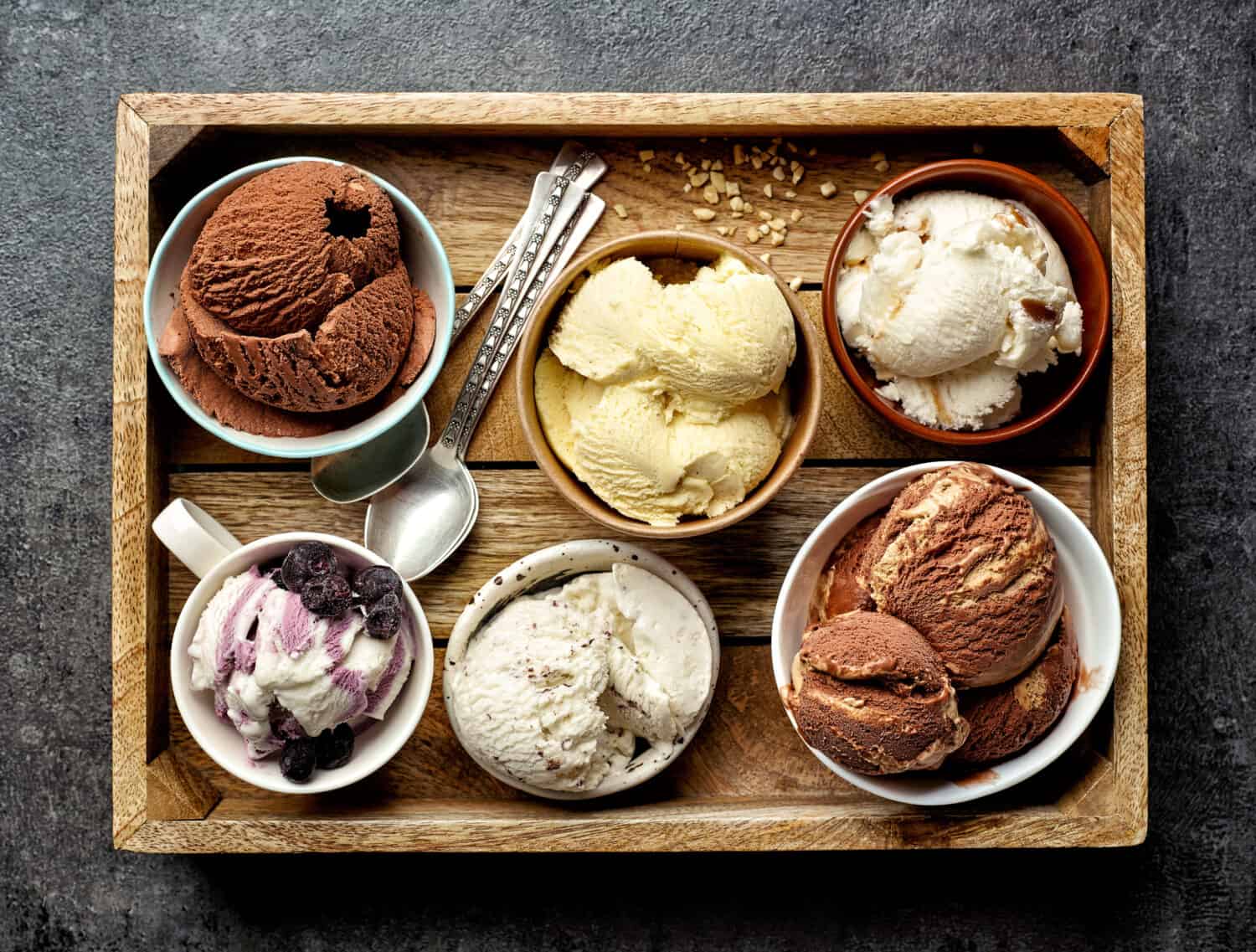 bowls of various ice creams on dark gray table, top view