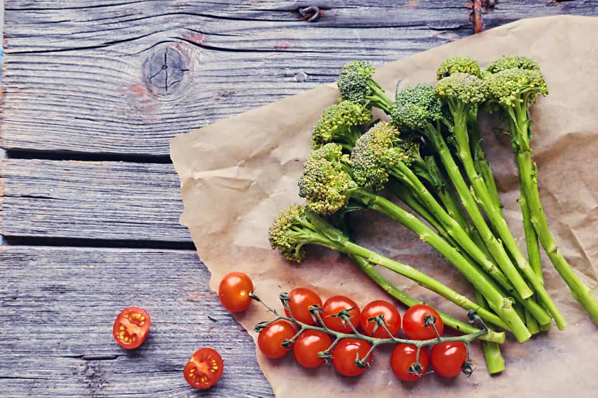 Tomatoes and broccoli on a wooden table.