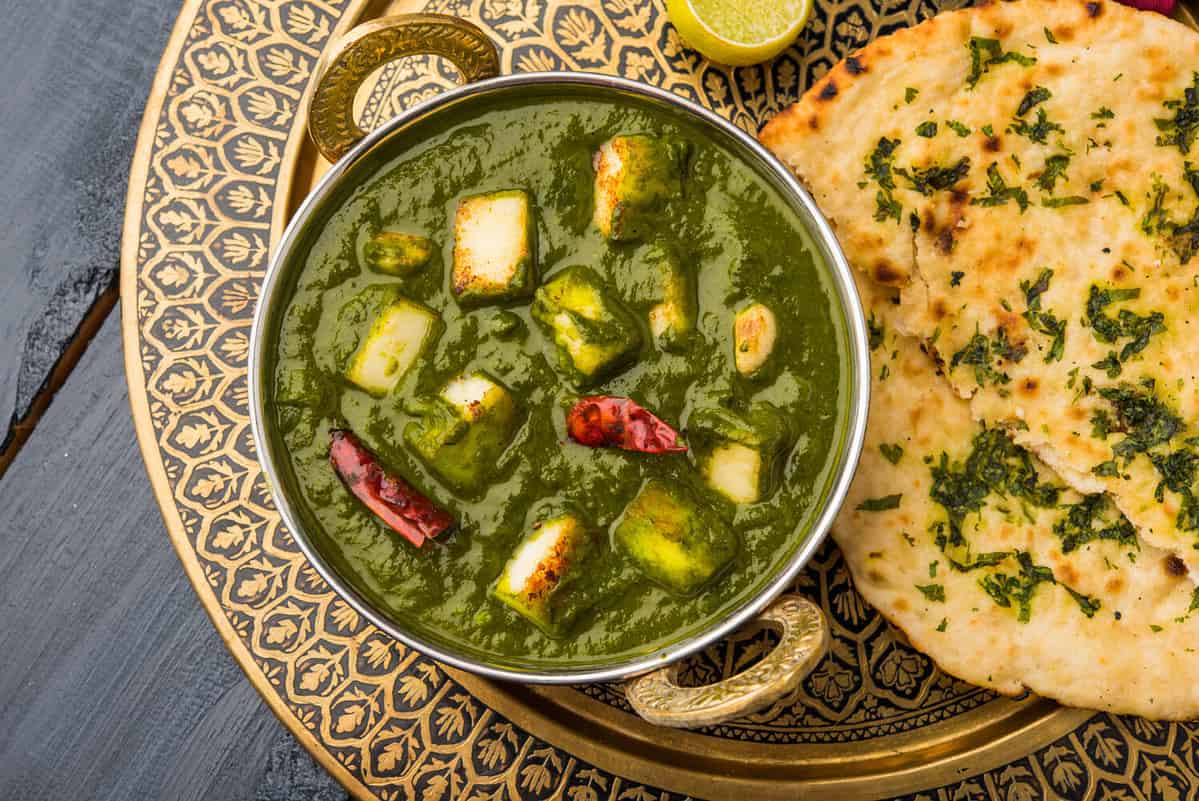 Palak Paneer Curry made up of spinach and cottage cheese, Popular Indian healthy Lunch/Dinner food menu, served in a Karahi with Roti Or Chapati over moody background. selective focus
