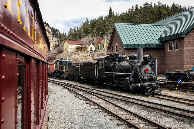 Steam locomotive of Georgetown loop railroad in Colorado, USA. Engine is parked in a depot, looking from another coach.