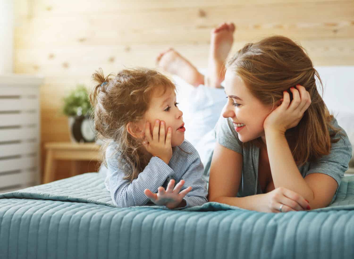 Happy family mother and child daughter play and laughing in bed