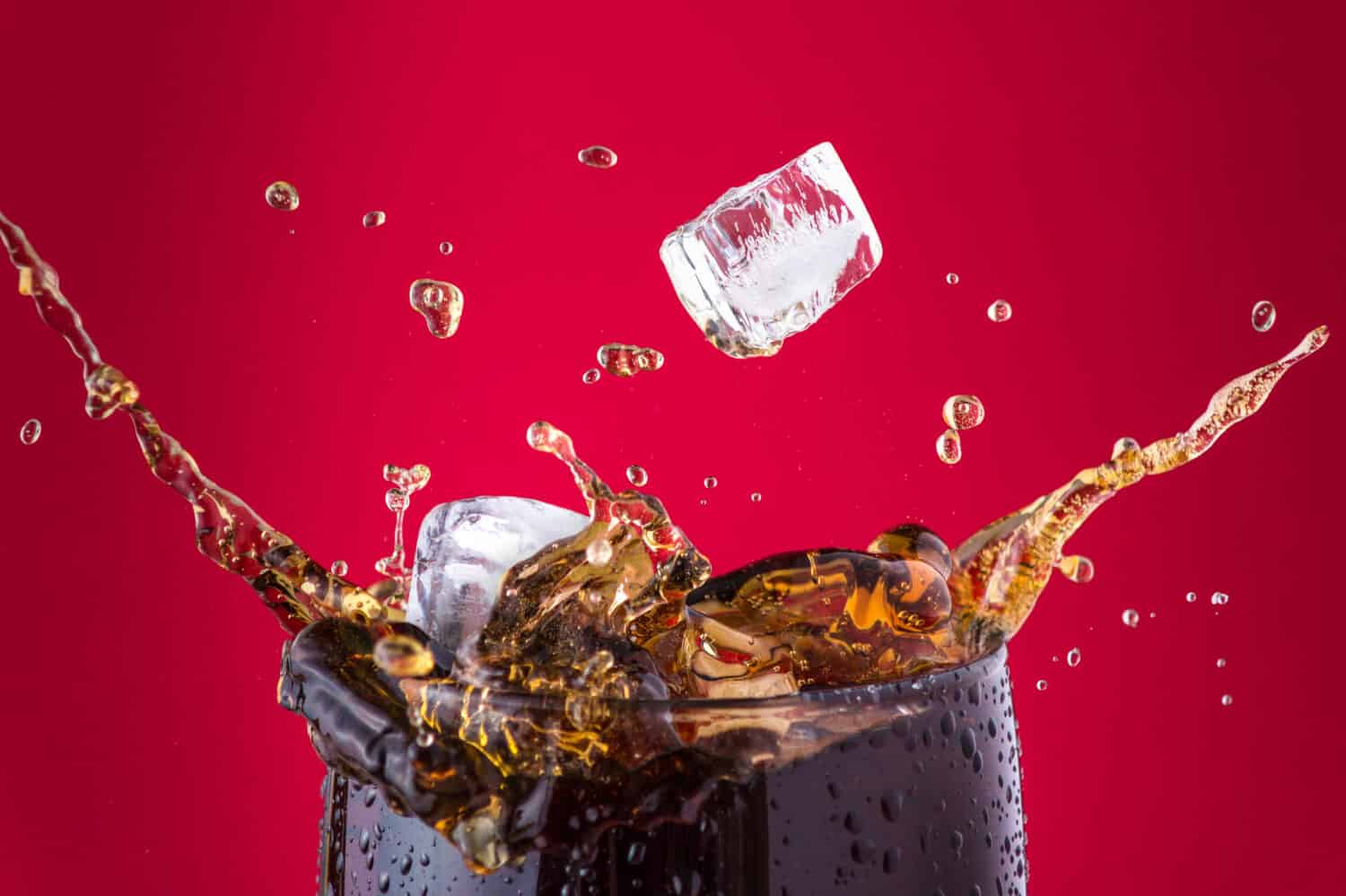 Ice cubes splashing into cola drink