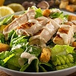 A delicious chicken caesar salad with parmesan cheese, dressing and croutons.