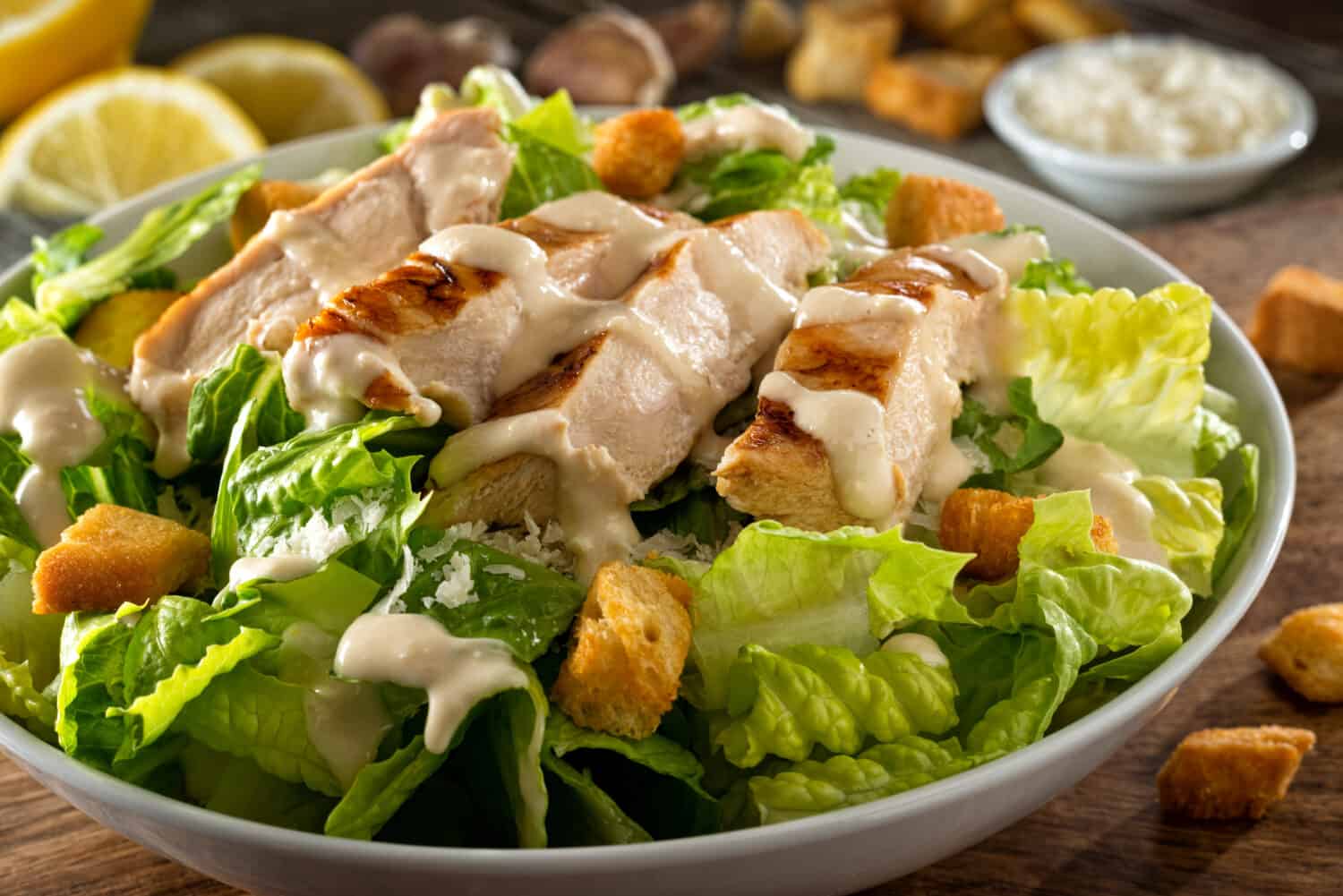 A delicious chicken caesar salad with parmesan cheese, dressing and croutons.