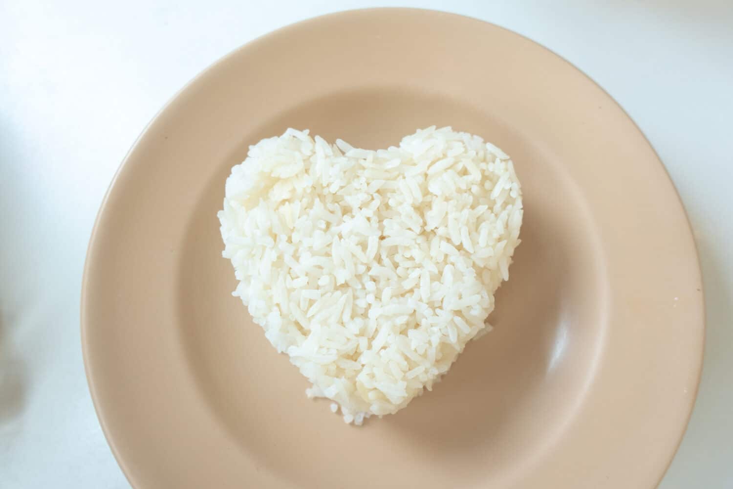 Heart shaped steamed rice served in small pink plate. Food preparing for meal concept.