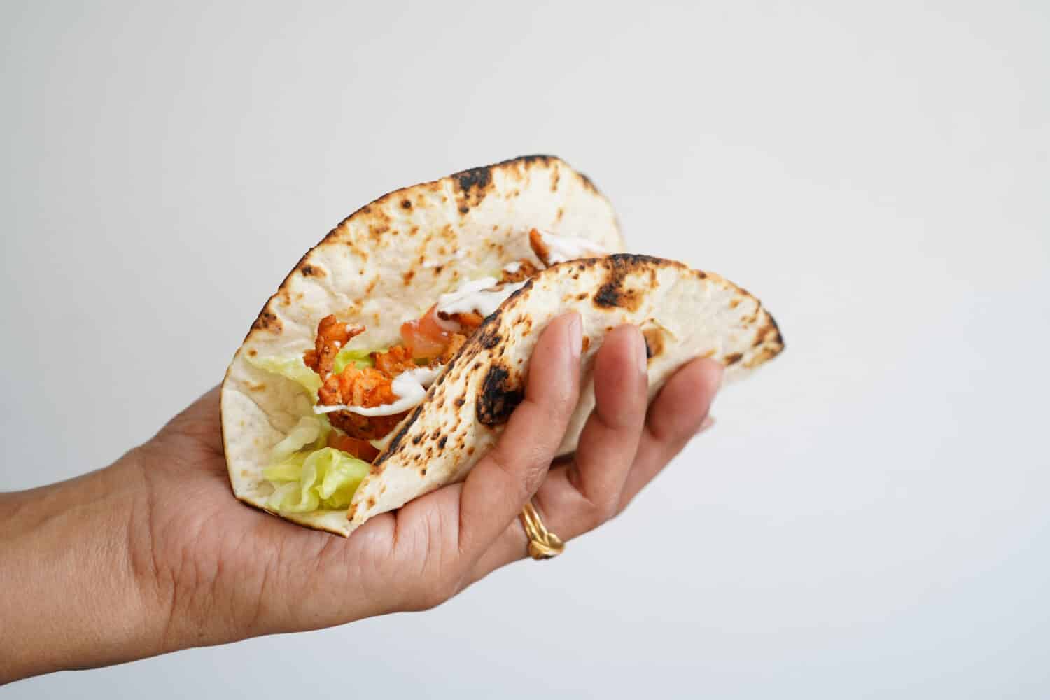 Female hand holding Soft fish tacos isolated on white, selective focus