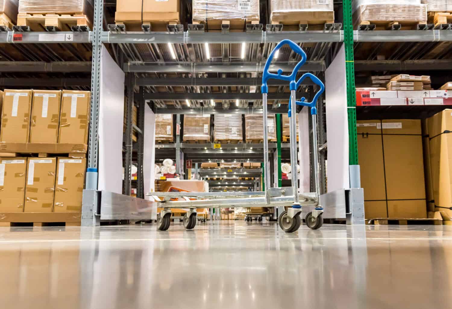 Warehouse storage of retail merchandise shop. Trolley Shopping Cart Between Dry Grocery Shelf Section in Supermarket Warehouse Retail Outlet as Shopping Concept.