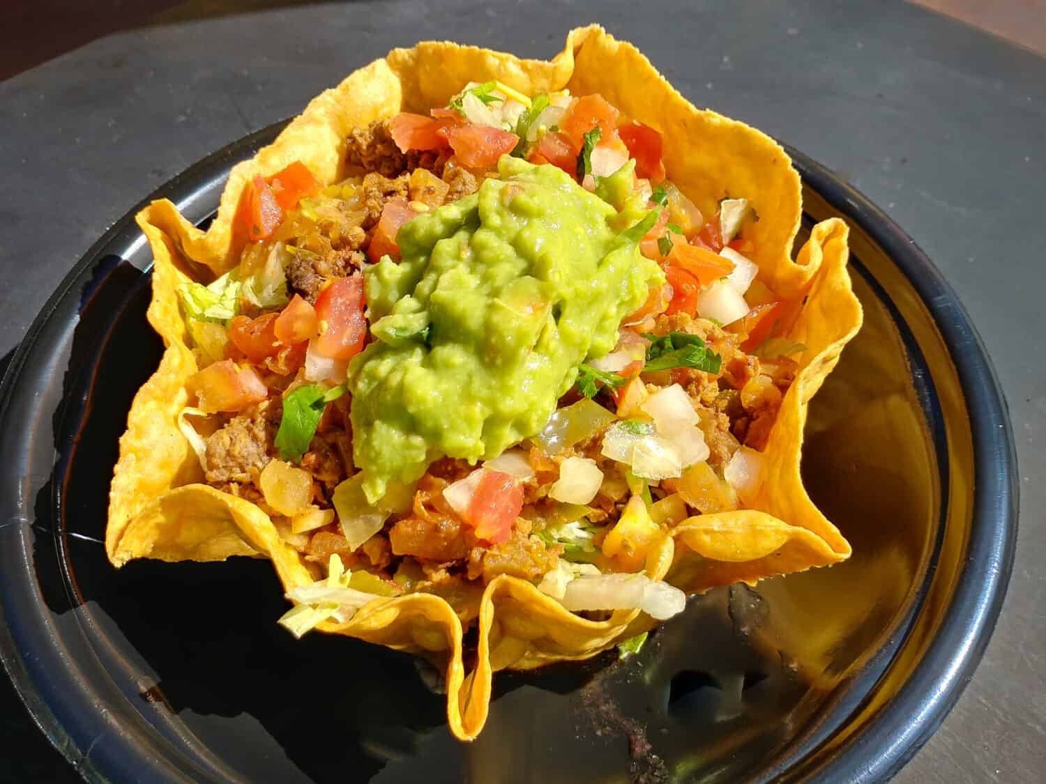 a delicious alternative meat taco bowl with rice black bean guacamole tomatoes and onions