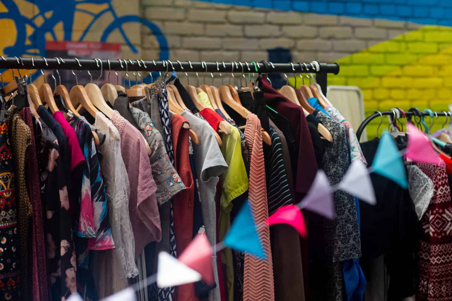 Colorful secondhand clothes on hangers at local market on the street