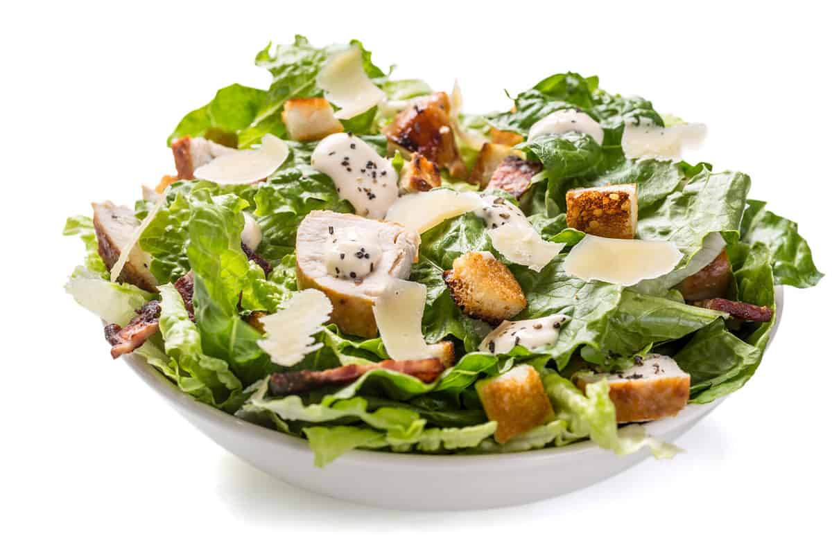 Bowl of Traditional Caesar Salad with Chicken and Bacon isolated on White Background