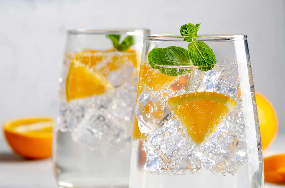 Hard seltzer cocktail with orange, mint and ice.