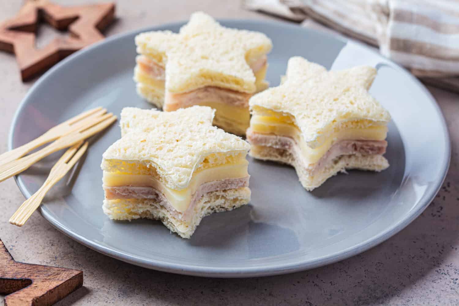 Christmas food - Star-shaped cheese and ham sandwiches on a gray plate. Festive food concept.