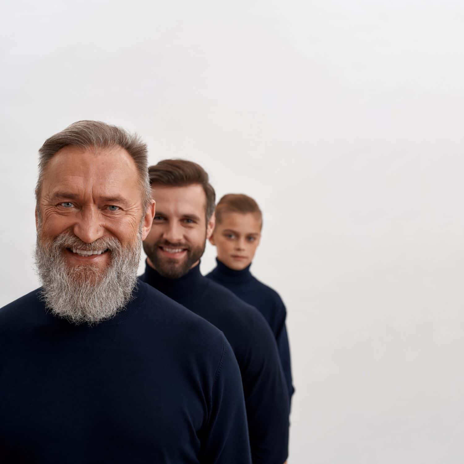 Crop narrow shot image portrait of smiling three family generation of men in row isolated on white studio background. Old grandfather forefront with young son and little grandson. Offspring.