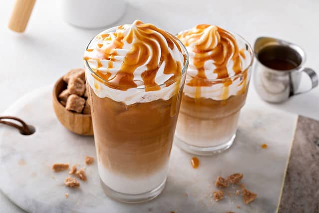 Iced caramel latte topped with whipped cream and caramel sauce, refreshing and sweet coffee drink