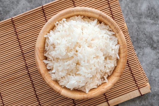 Top Table View Of Thai Jasmine Rice in Wooden Bowl, staple food of Thailand and Asia, providing energy in every meal.