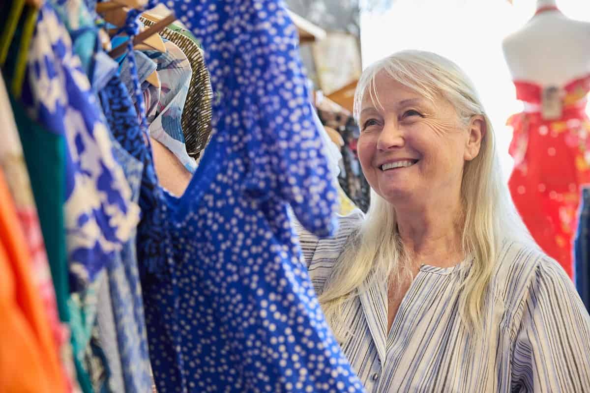 Senior Woman Buying Used Sustainable Clothes From Second Hand Charity Shop Or Thrift Store