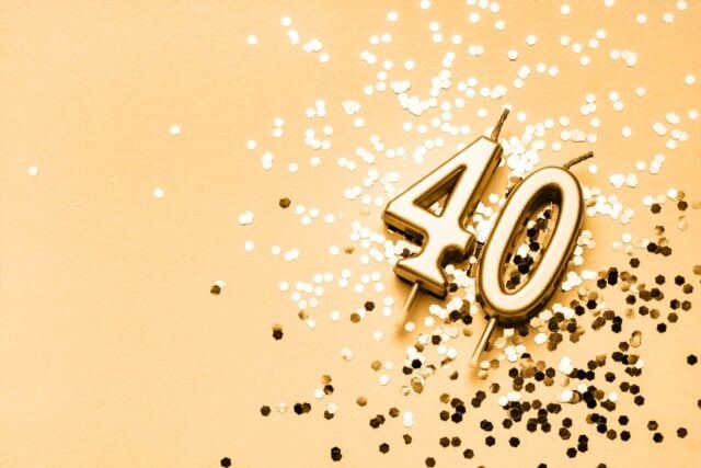 40 years celebration festive background made with golden candles in the form of number Forty lying on sparkles. Universal holiday banner with copy space.