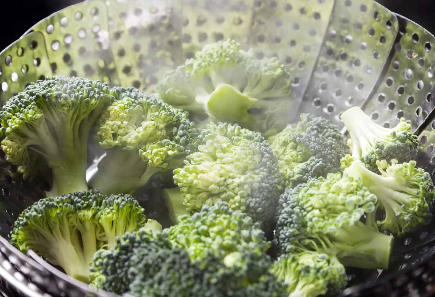 Freshly steamed green broccoli in skimmer pot with steam