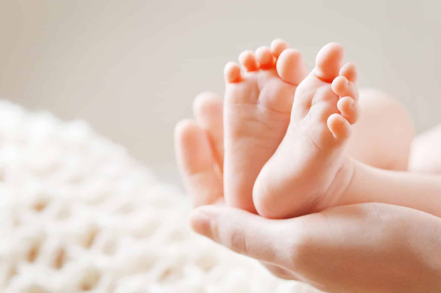 Baby feet in mother hands. Mom and her Child. Happy Family concept. Beautiful conceptual image of Maternity