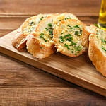 Tasty bread with garlic, cheese and herbs on kitchen table