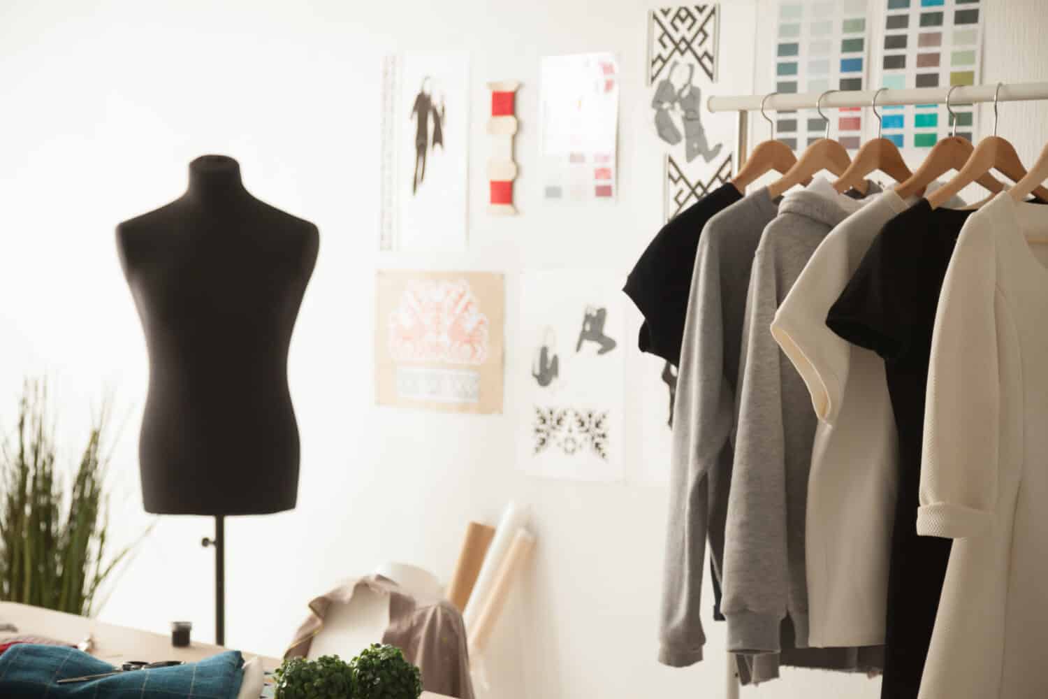 Fashion creative design studio cozy interior concept with mannequin dummy and exclusive unique stylish fashionable trendy clothes on hangers, dressmaking workplace, tailor shop, sewing workshop