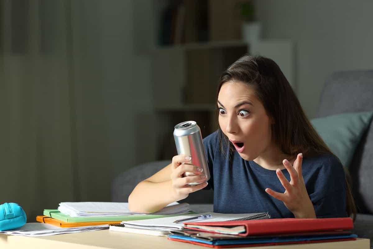Amazed student looking at energy drink in the night at home