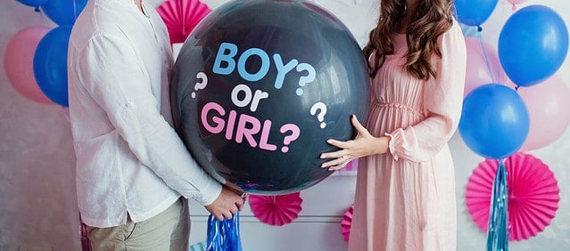 man and woman holding black balloon with "boy or girl?" on gender reveal party