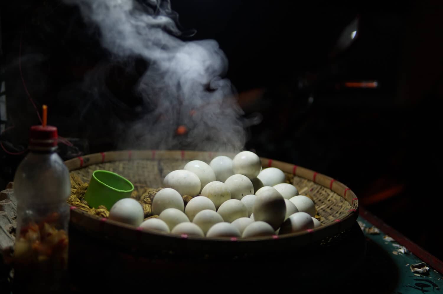 A steaming pile of balut, a duck egg delicacy in the Philippines, placed together with shelled peanuts on a bilao, or a traditional woven tray.