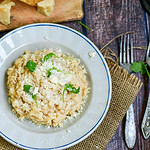 Italian creamy cheese risotto with parmesan cheese and fresh basil on rustic background
