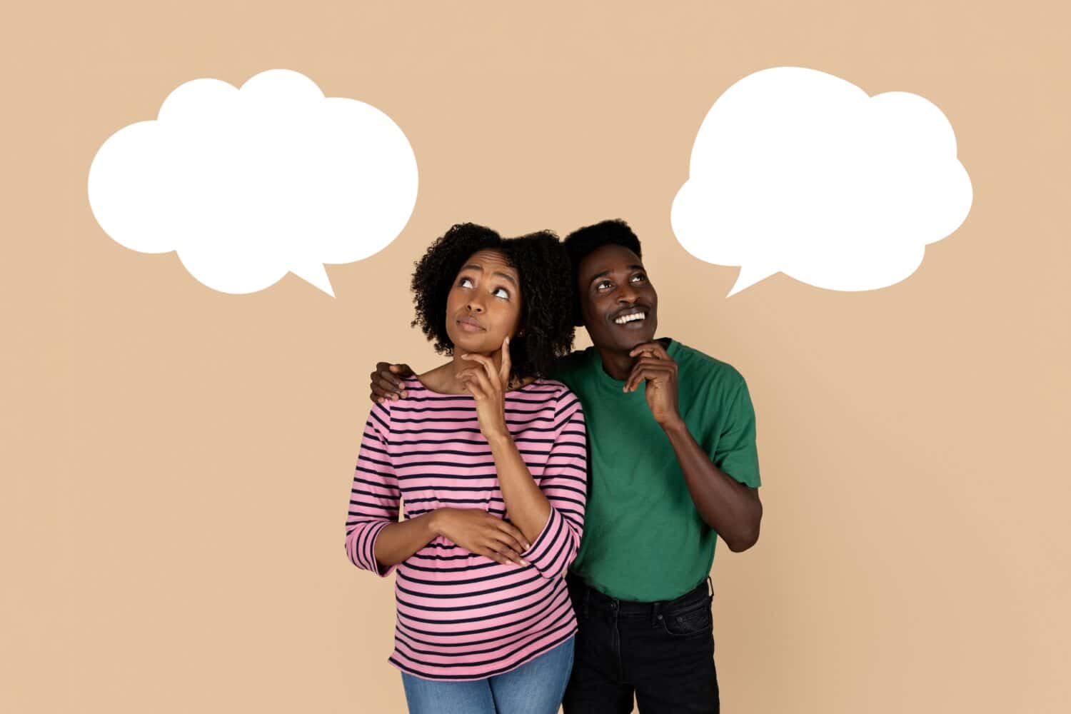 Smiling pensive black millennial husband and wife enjoy pregnancy, think, choose name with abstract bubble for thought, isolated on beige background, studio. Family lifestyle and expecting baby