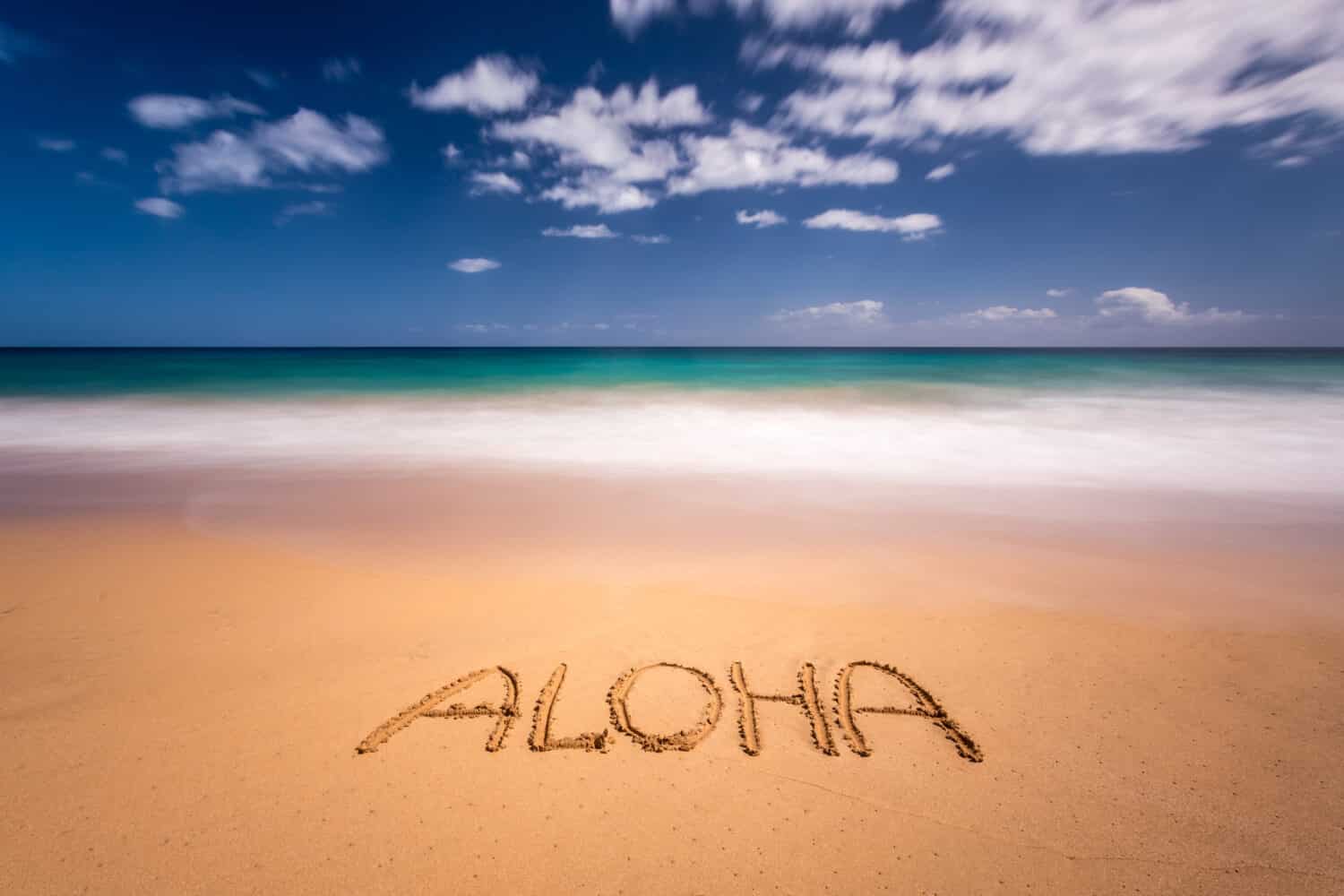 Aloha written in the sand on the beach of Kapaa, Kauai, Hawaii