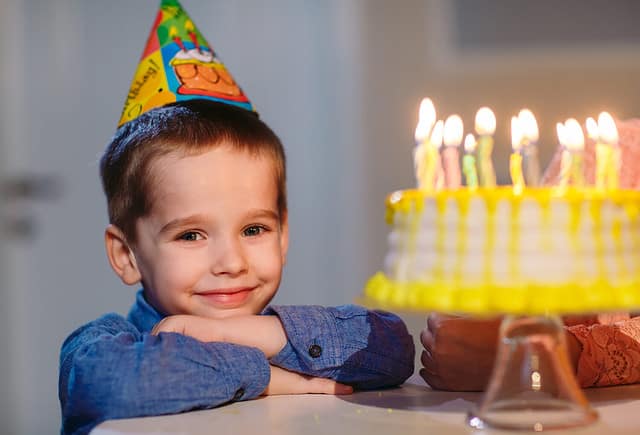 Children's birthday. Children near a birthday cake with candles.