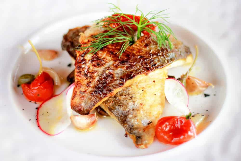 Grilled red snapper with burnt butter, capers, tomato and lemon sauce. Fresh seafood dish in restaurant, Phuket, Thailand.
