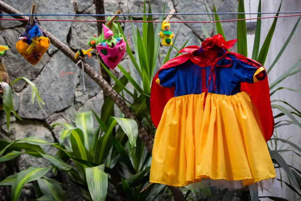 Concept: Trick or Treat. Getting ready for a kids costume party. Little snow whites dress hanging in the backyard. Halloween kids costume party.