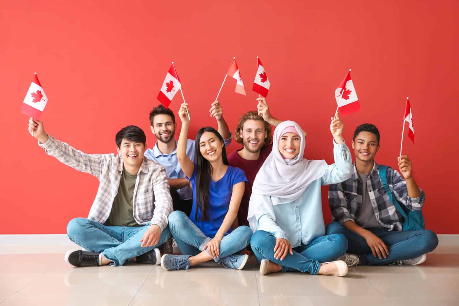 Group of students with Canadian flags sitting near color wall