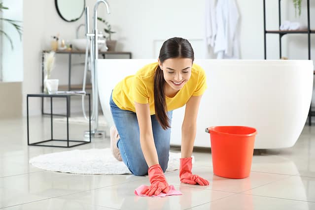 Beautiful young woman cleaning bathroom