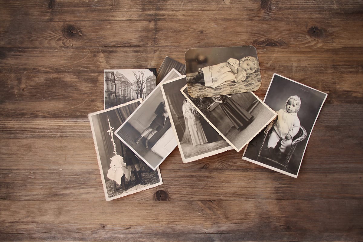 old vintage monochrome photographs are scattered on a wooden table, photographs of his and his sisters, pictures taken in 1964, concept of genealogy, the memory of ancestors, family ties, memories