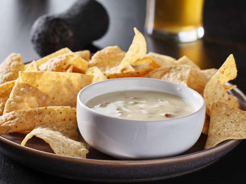 mexican hot queso blanco cheese dip with corn tortilla chips on plate