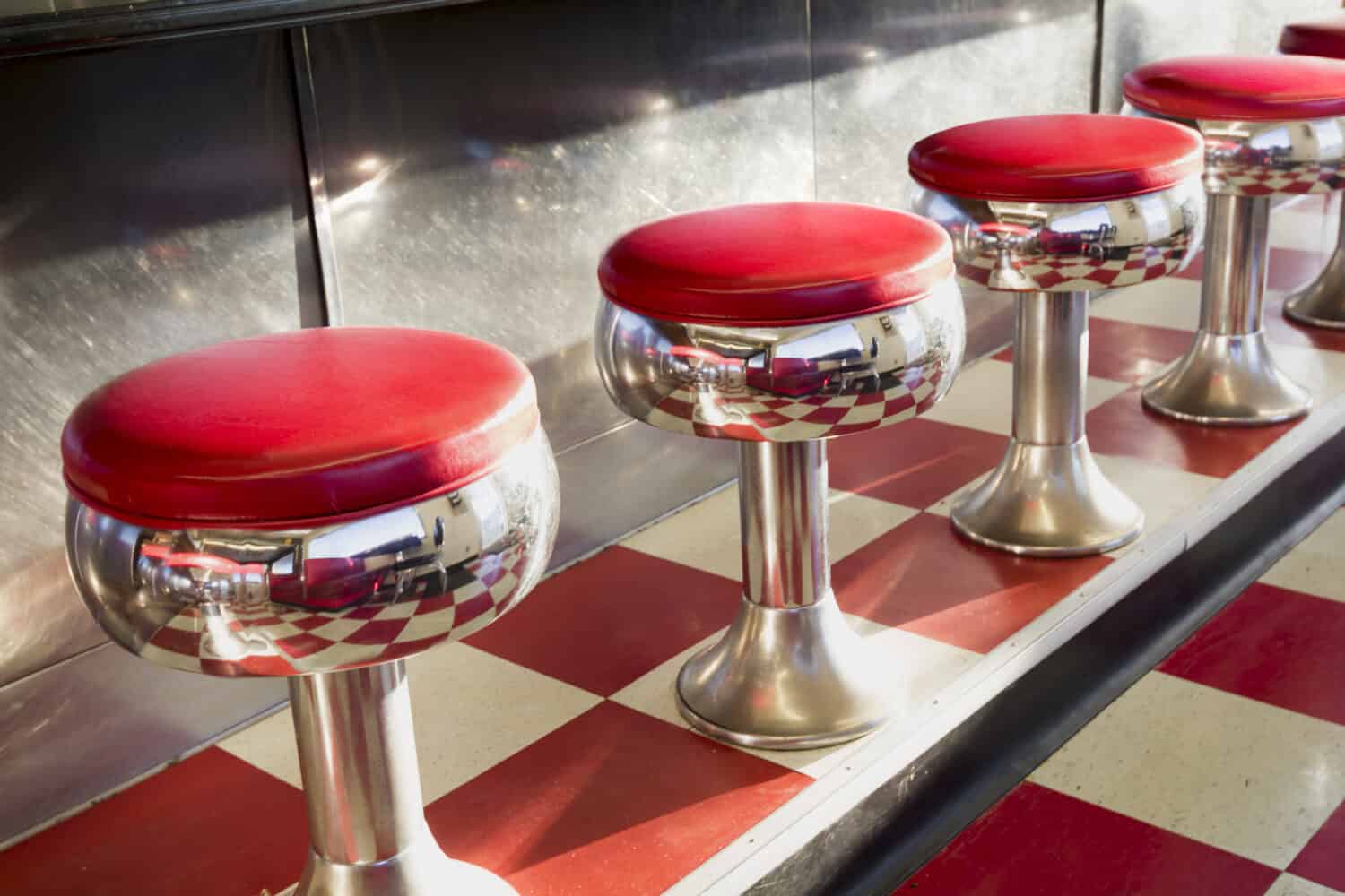 Warm morning sunlight highlights the simple but beautiful design of this classic diner counter with it's galvanized steel counter, bright chrome seats with red padding and bright red tiles.