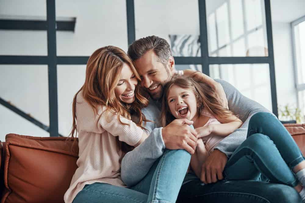 Happy young family smiling and embracing while bonding together at home