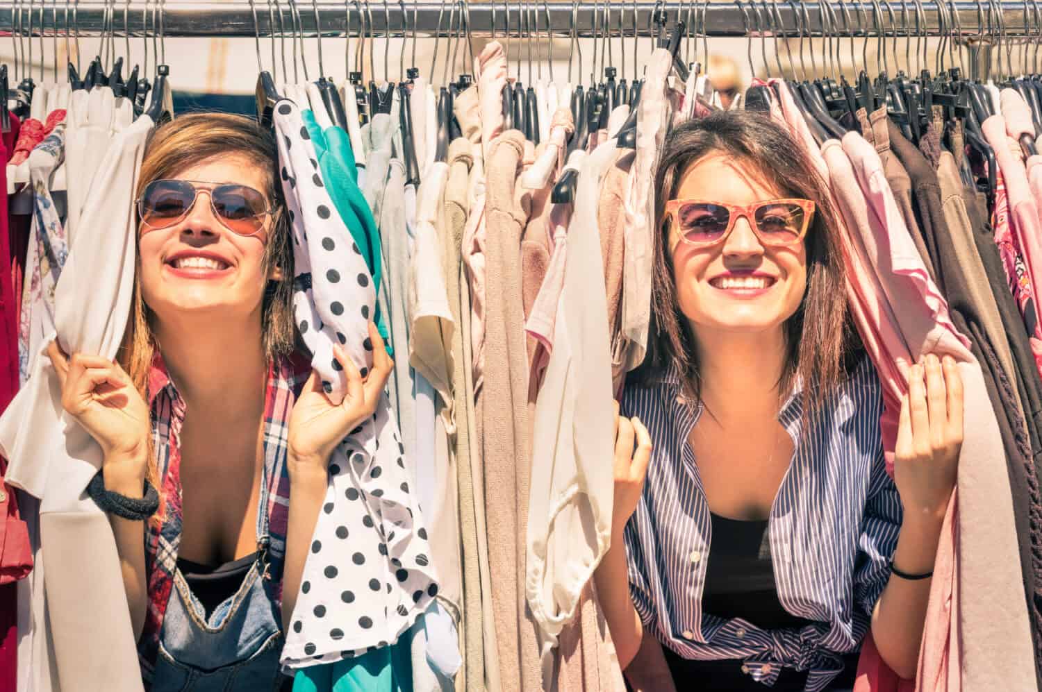 Young beautiful women at weekly cloth market - Best friends sharing free time having fun and shopping in old town on sunny day - Girlfriends enjoying everyday life moments - Looking at camera view