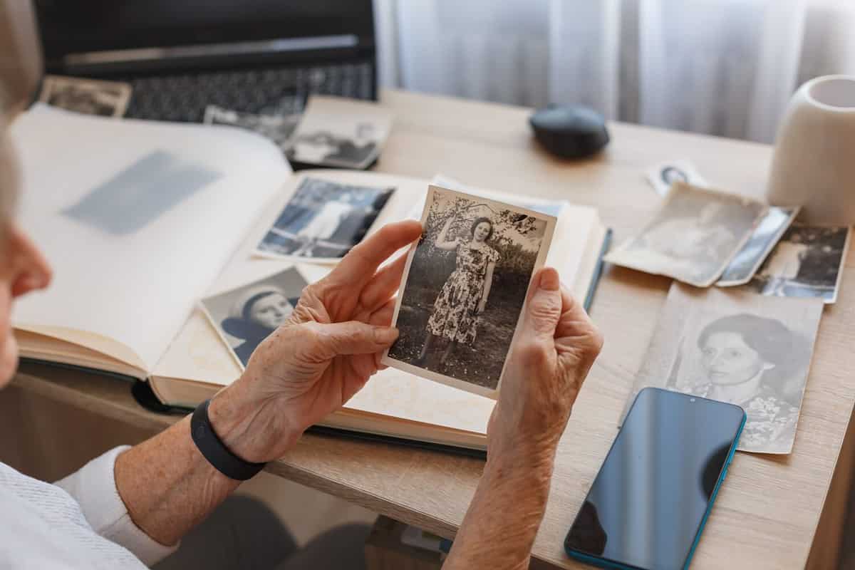 Senior woman is looking her own old photos at home. Elderly woman has got smile while remembering how young and beatiful she was. Selective focus. Photo was taken in 1953 Bollam family