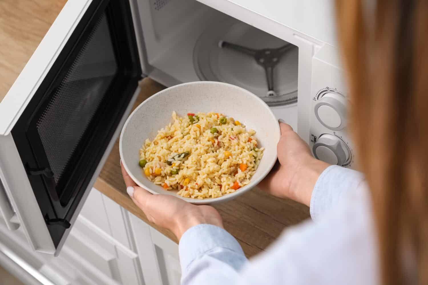 Woman heating food in microwave oven